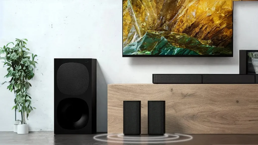 Speakers on floor with a TV & Soundbar behind.